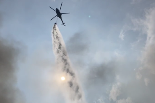 Water gushing from helicopter to control fire